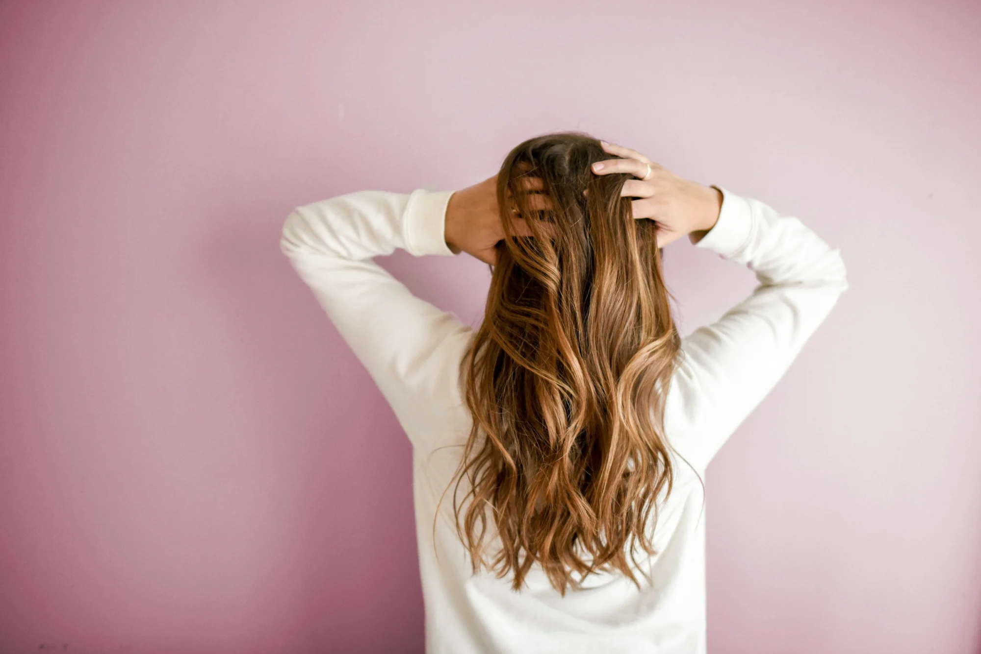Frau mit langen Haaren vor rosa Hintergrund