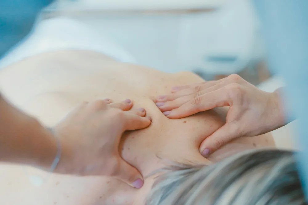 Hände einer Therapeutin am Rücken eines Patienten